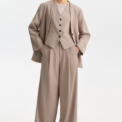 Modelo vestindo fato feminino cinza claro riscado com colete e calças largas, óculos escuros