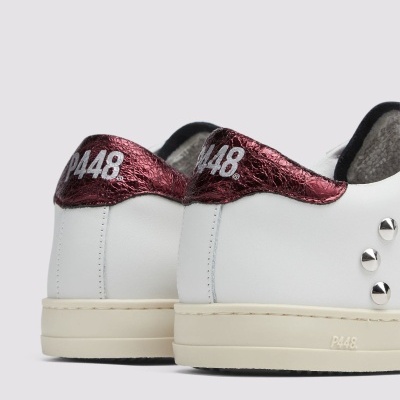 Ténis brancos com detalhes vermelhos metálicos e tachas prateadas