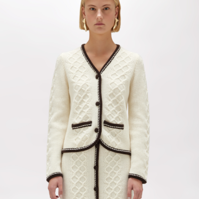 Conjunto de malha branco com casaco e saia, padrão trançado e bordas pretas com branco.