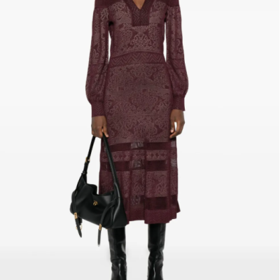 Vestido midi bordô com padrão floral e geométrico, decote em V, mangas compridas, botas pretas e mala preta.