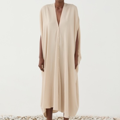 Vestido comprido bege claro com botões e sandálias castanho escuro em superfície de pedras