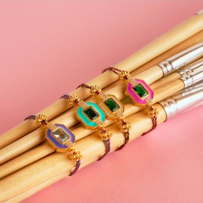 Quatro pulseiras coloridas com pedras verdes sobre pincéis de madeira