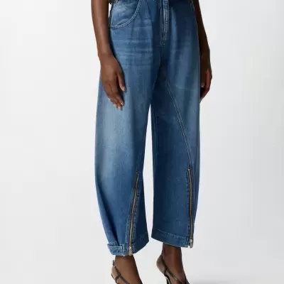 Calças largas de ganga azuis com fechos e sapatos de salto pretos.