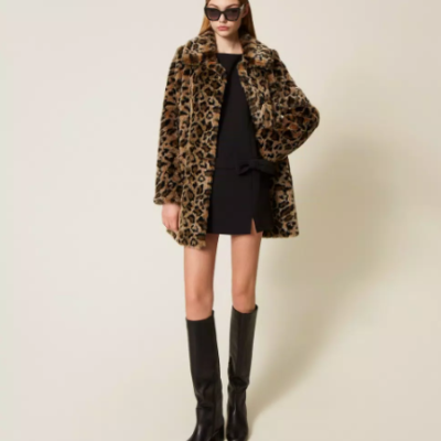Modelo veste casaco de pelo sintético leopardo, vestido preto, botas pretas e óculos de sol