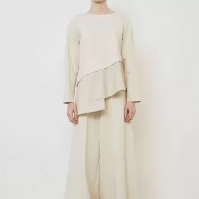 Conjunto bege claro com blusa de sobreposição e calças largas.