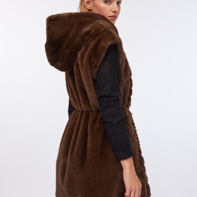 Colete castanho felpudo com capuz usado por mulher com suéter azul escuro