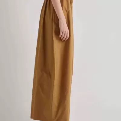 Mulher com saia castanha comprida e sapatos brancos com rede