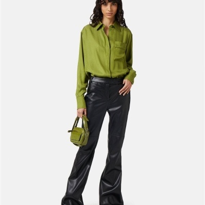 Modelo com camisa verde clara, calças pretas largas e bolsa verde clara