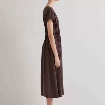 Mulher vestindo vestido midi castanho escuro com listras verticais e sapatos prateados.