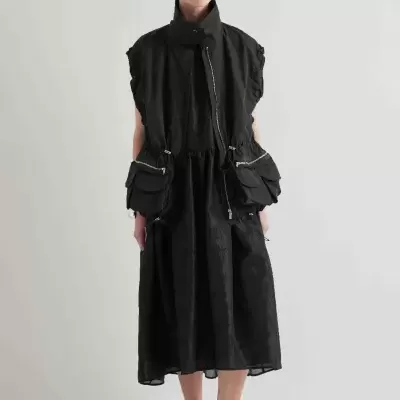 Vestido midi preto com textura floral e colete preto com bolsos grandes em modelo feminino