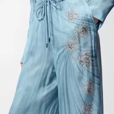 Calças azuis claras com bordados florais e folhas cinzentas, cós elástico e cordão ajustável