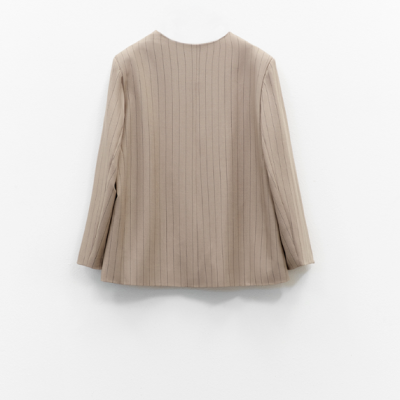 Casaco bege de riscas verticais pendurado numa parede branca