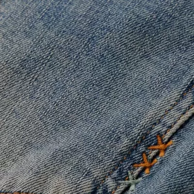 Tecido de ganga azul com costuras castanhas e bordado decorativo