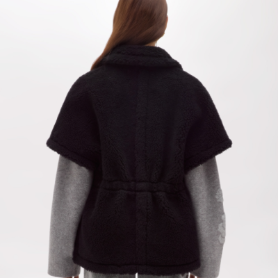 Casaco curto preto felpudo com cinto e mangas cinza claro visto de costas