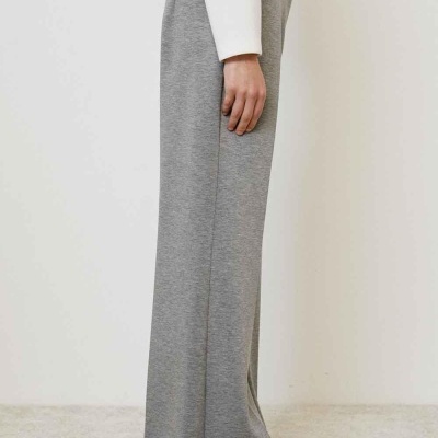 Calças cinzentas largas, camisa branca e chão claro