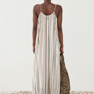 Vestido comprido às riscas visto de costas com sandálias castanhas e mala trançada.