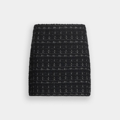 Saia curta preta xadrez texturizada com linhas brancas e emblema metálico