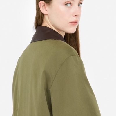 Casaco verde com gola castanha visto de trás, mulher com cabelo castanho