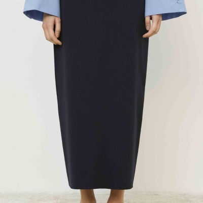 Saia preta comprida com camisa azul clara e sapatilhas pretas