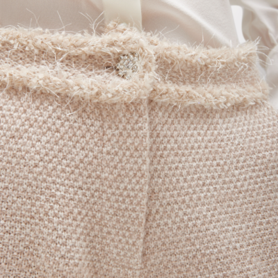 Saia bege texturada com cinto felpudo e botão prateado, com camisa branca