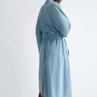 Casaco comprido azul claro de ganga com cinto e fenda lateral em fundo branco