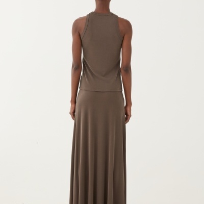 Conjunto castanho com t-shirt sem mangas e saia comprida visto de costas sobre pedras brancas.