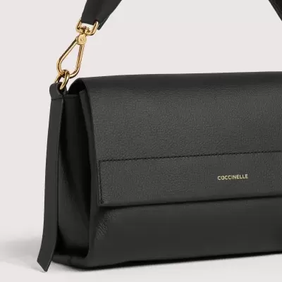 Bolsa preta de pele COCCINELLE com alça preta e detalhes dourados em fundo cinza