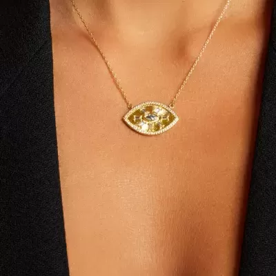 Colar dourado com pendente em forma de olho e pedras usadas ao pescoço