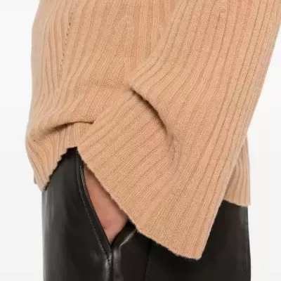 Camisola castanha canelada e calças pretas em couro com mão no bolso