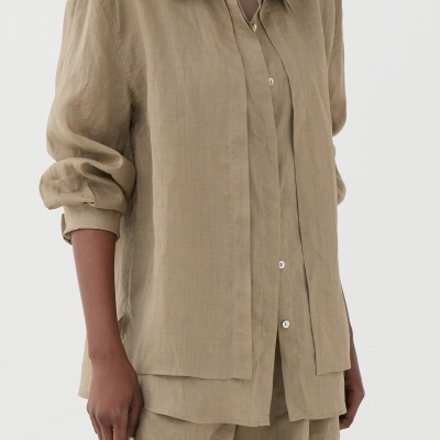 Conjunto bege claro de camisa e calções para mulher com botões coloridos e mangas da camisa arregaçadas.