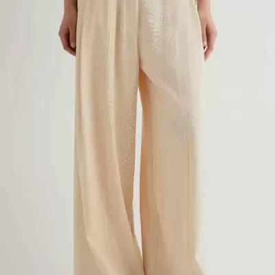 Calças largas bege claro com textura e cintura alta, em fundo branco