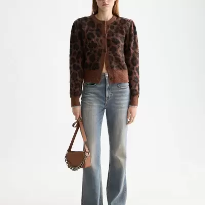 Mulher com cardigan castanho padrão animal print, calças ganga azuis largas, sapatos pretos, óculos escuros e mala castanha com corrente.