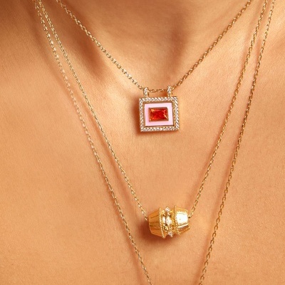 Colares dourados com pendentes variados em detalhe no pescoço.