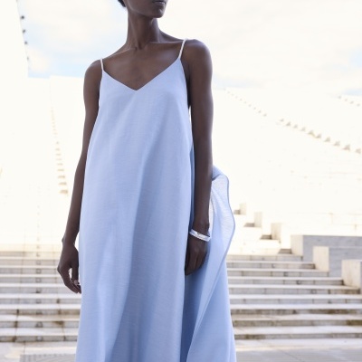 Mulher com vestido comprido azul claro com alças finas e decote em V.