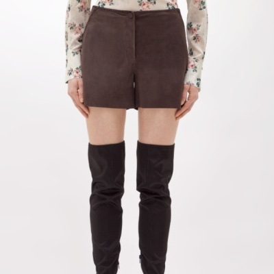 Shorts castanhos camurça com camisa floral e botas pretas.