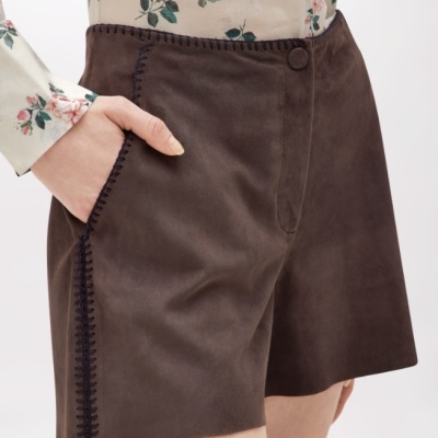 Calções castanho escuro em tecido tipo camurça com costura decorativa e blusa floral creme