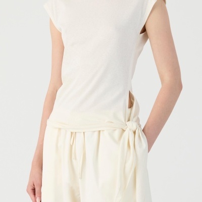 Top branco de manga curta com amarração lateral e calças largas brancas.