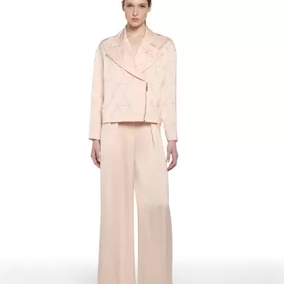 Mulher com casaco e calças rosa claro com padrão triangulares