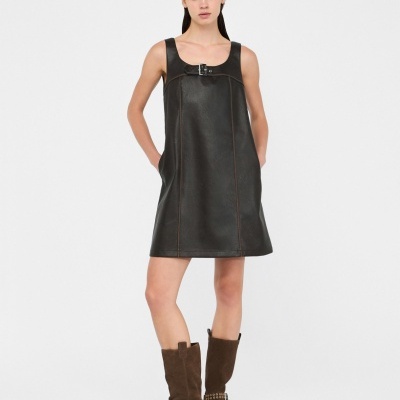 Vestido preto de pele sintética com cinto e botas castanhas de camurça em fundo branco