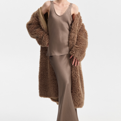 Mulher com camisola taupe, saia comprida, casaco de pelo castanho e sapatos de salto