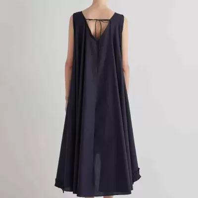 Vestido comprido azul escuro com costas decotadas e laço, usado com sapatos brancos