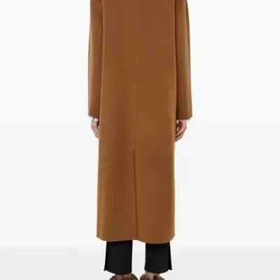 Casaco castanho comprido visto de costas com calças pretas e sapatos peludos castanhos