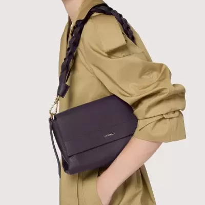 Mala de ombro roxa em pele com alça trançada numa mulher com casaco cáqui