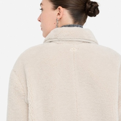 Casaco bege de pelo sintético visto de costas numa mulher com cabelo apanhado