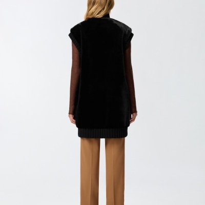 Modelo de costas com colete preto, camisa castanha e calças castanhas.