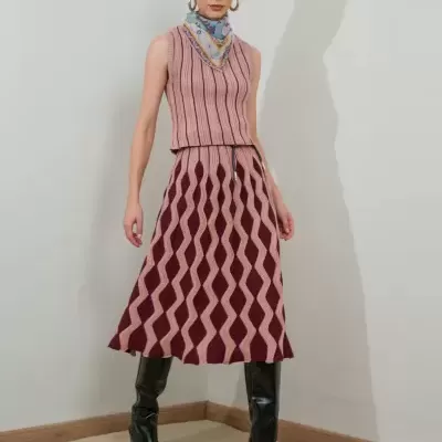 Mulher vestindo conjunto rosa e vinho com botas pretas e lenço azul