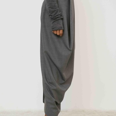 Calças cinza largas com sapatos cinza escuro e camisola de manga comprida.