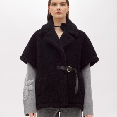 Colete peludo preto com cinto fechado e camisa cinzenta com padrão floral em relevo