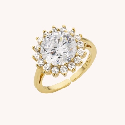 Anel de metal dourado com pedra redonda branca central e pequenas pedras ao redor