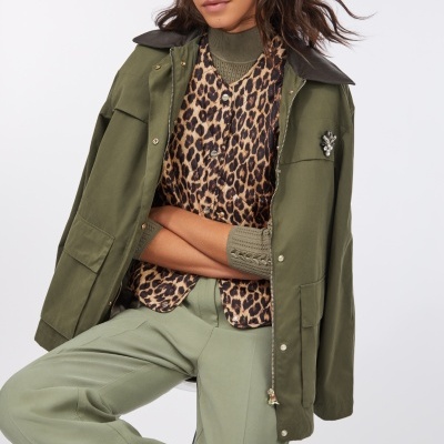 Mulher vestindo blusão verde-oliva, camisa de padrão leopardo e calças verdes